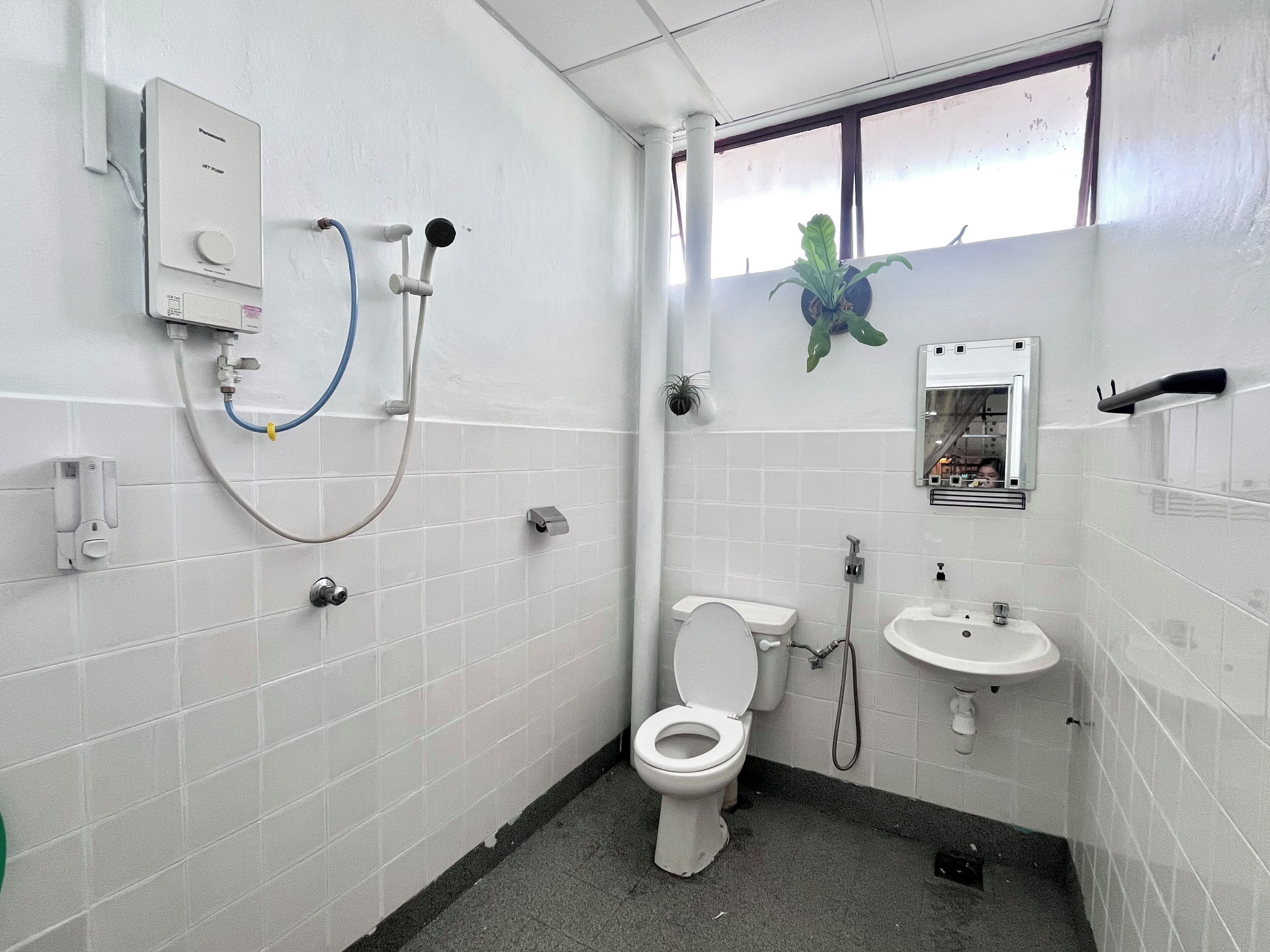 Egy kis, tiszta fürdőszoba, amelyben WC, mosdókagyló és zuhanyzó található.