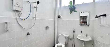 Egy kis, tiszta fürdőszoba, amelyben WC, mosdókagyló és zuhanyzó található.
