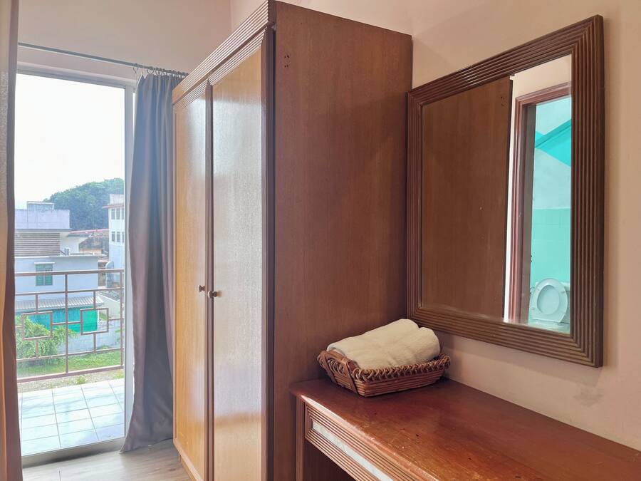 Una habitación con un armario de madera, un espejo y una pequeña mesa de madera con una toalla.