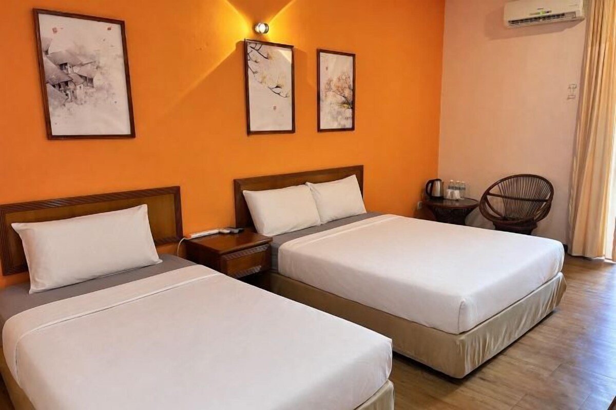 Een hotelkamer met twee bedden, een nachtkastje, een stoel en lijstjes met kunstwerken aan de muur.