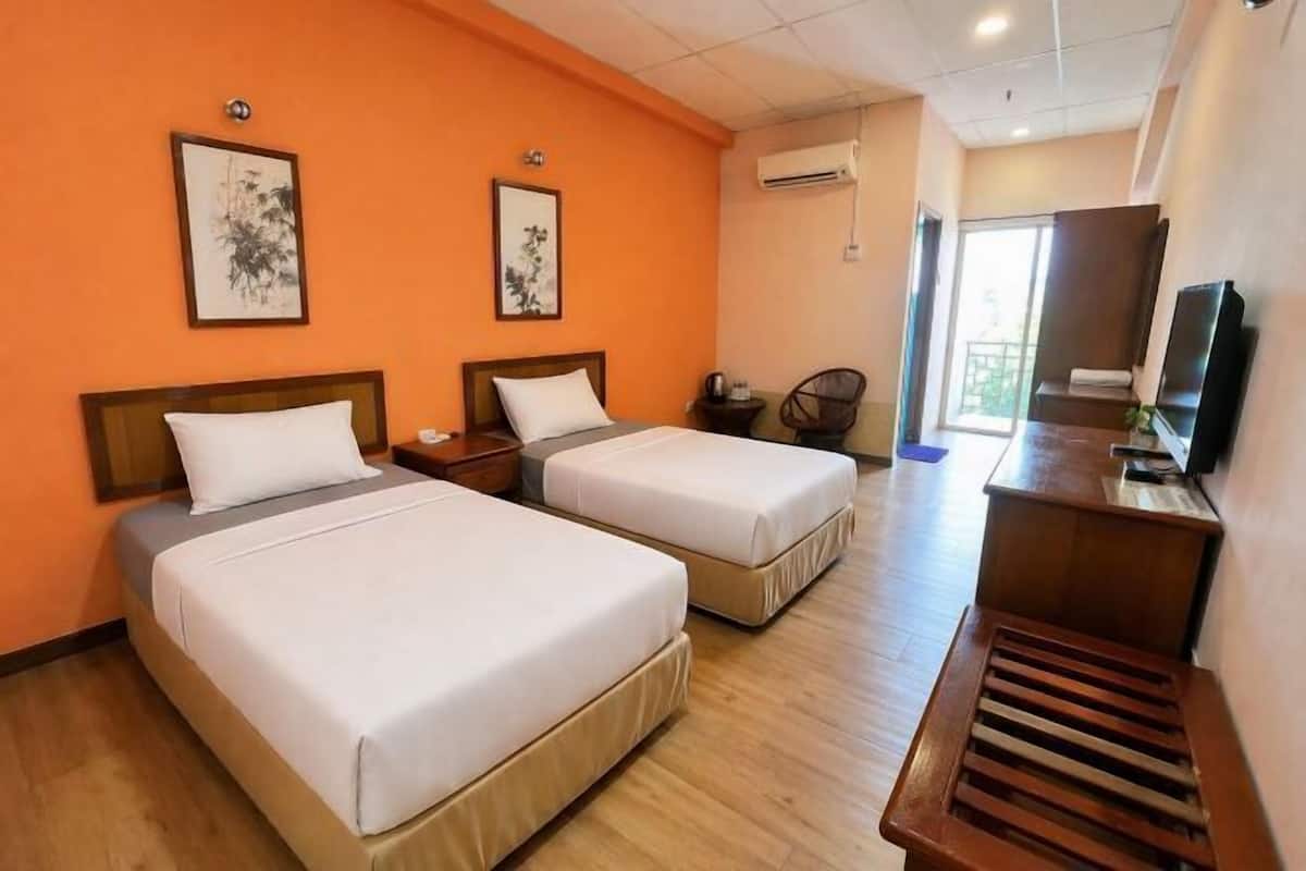 A hotel room with two beds, a desk, a chair, and artwork on the walls.