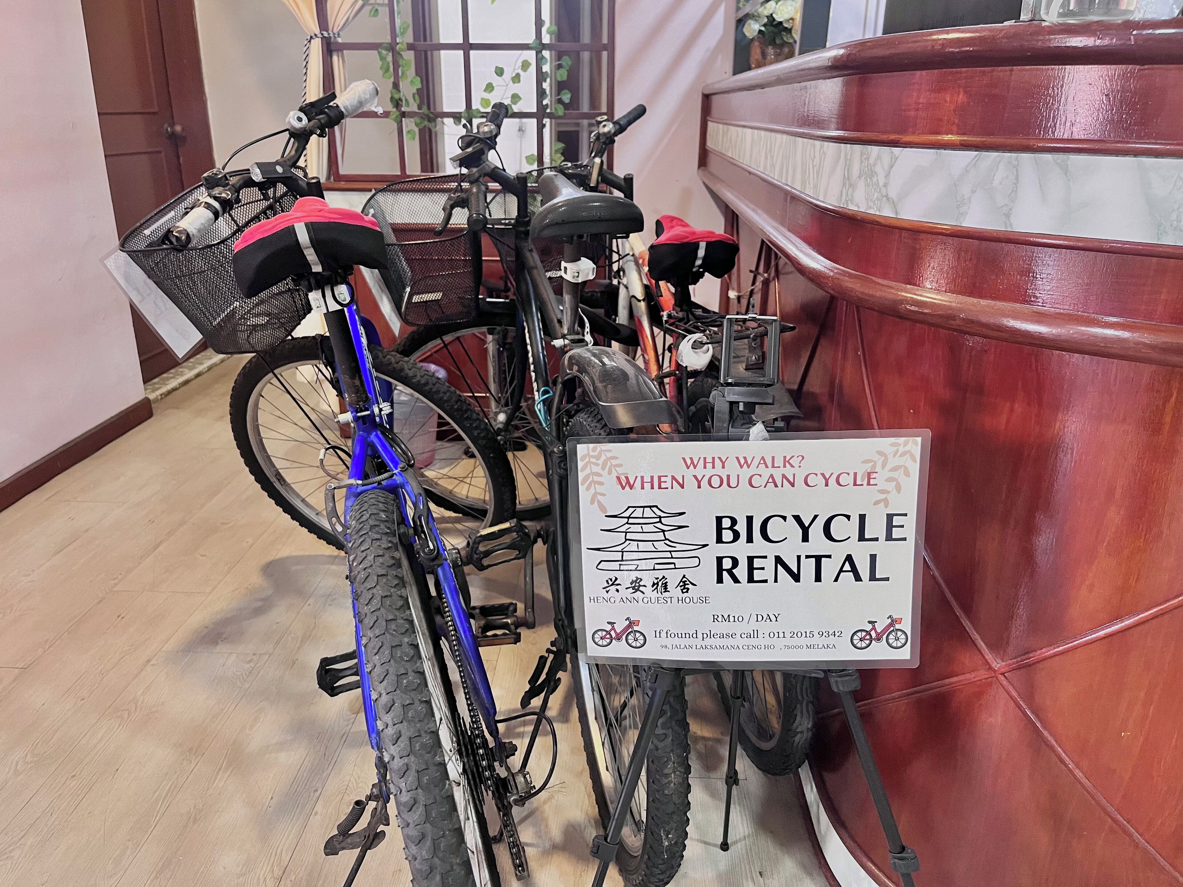 Une pancarte indiquant un service de location de vélos, dans une pièce au plancher en bois et dotée d’un meuble rouge.