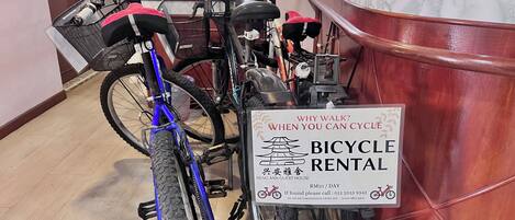 Un cartel de alquiler de bicicletas en una habitación con suelo de madera y un armario rojo.