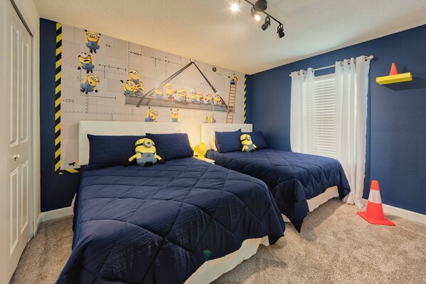 Een slaapkamer met twee bedden, een muurschildering van Minions, een ladder en een kleine oranje kegel op de vloer.