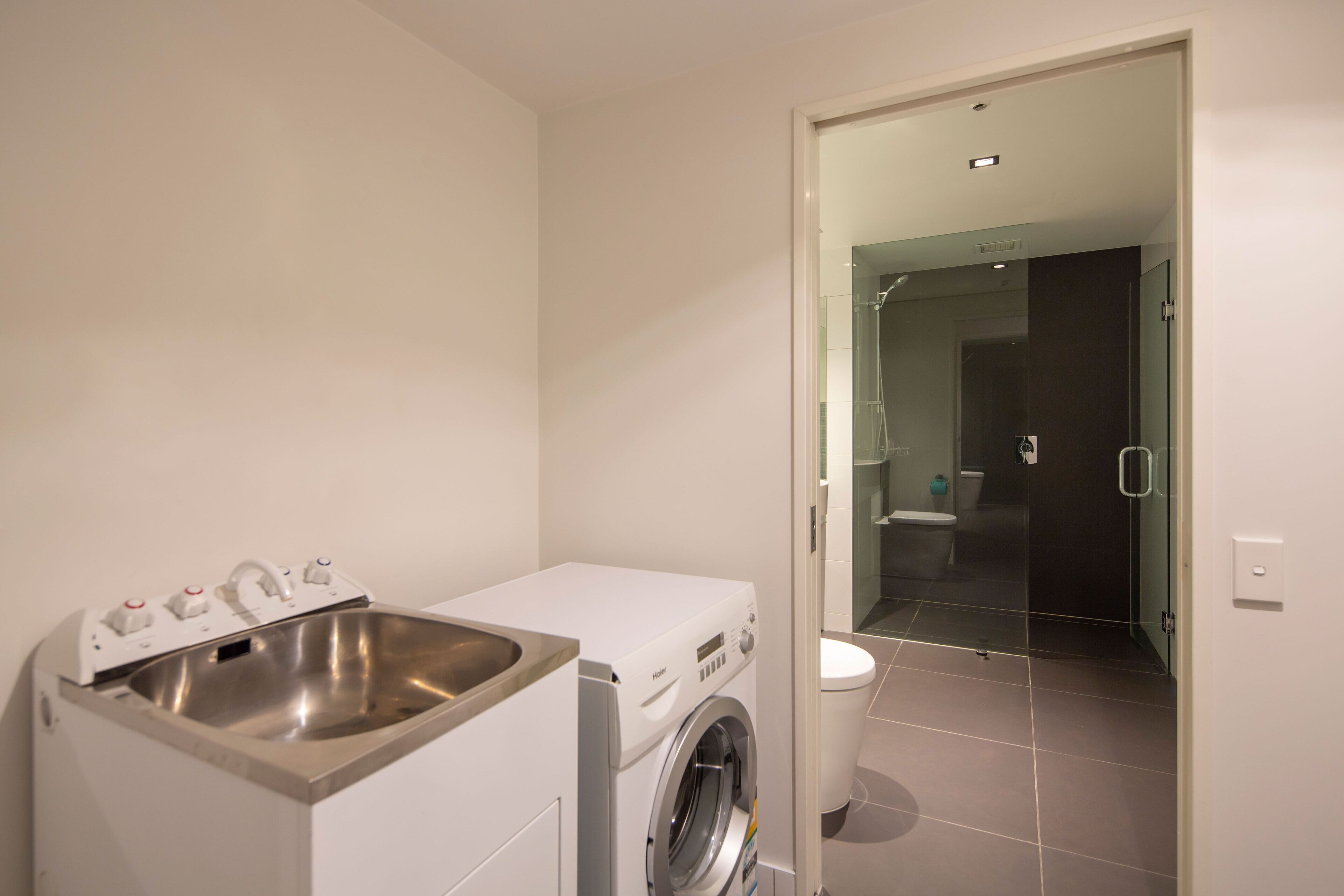 Un baño moderno y funcional con lavadora integrada, un lavamanos y un inodoro.