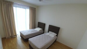 Ein Zimmer mit zwei Einzelbetten, Holzböden und einem großen Fenster mit Vorhängen.