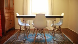 A dining area with a table and chairs, a wooden cabinet, and a patterned rug.