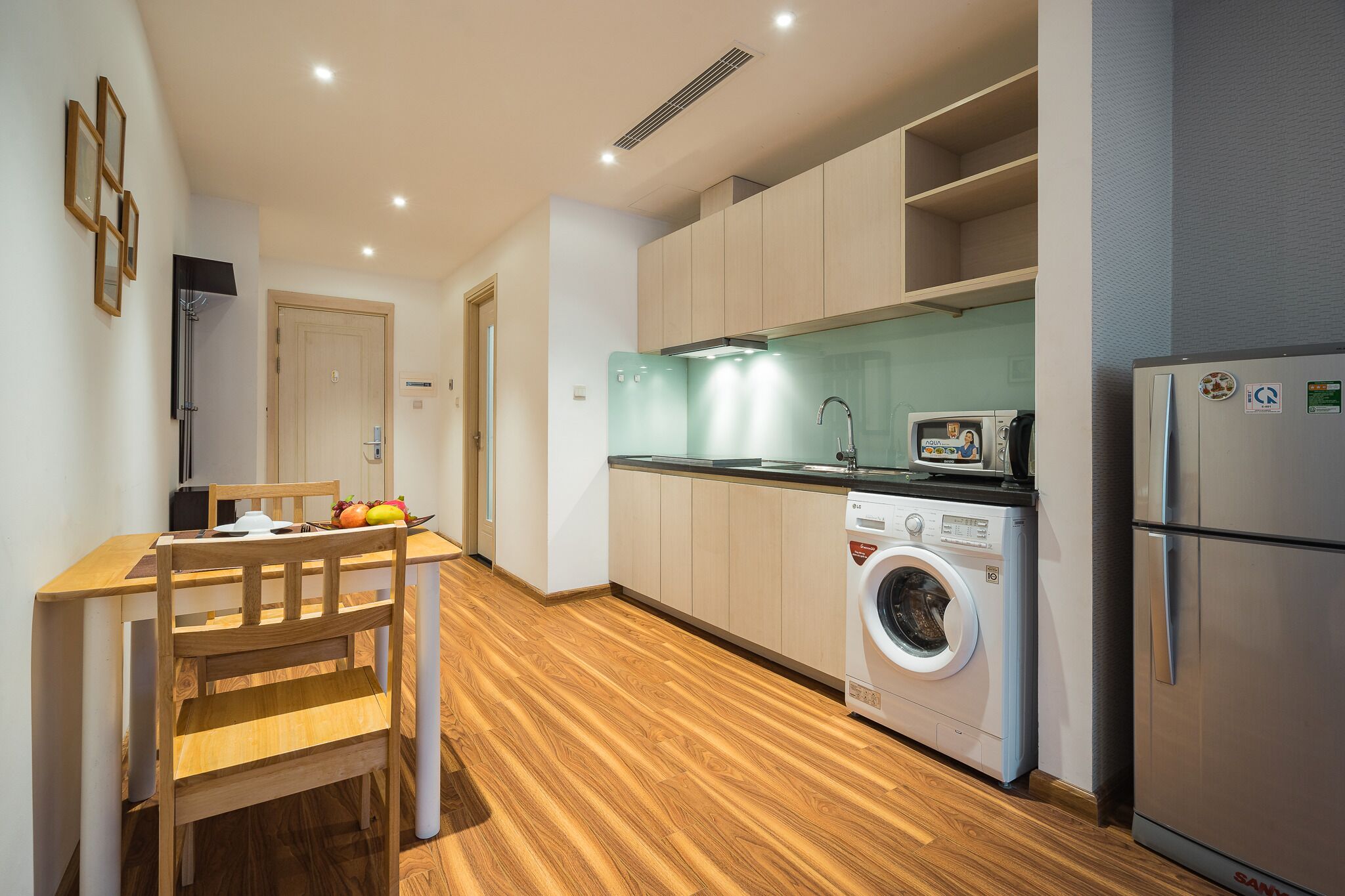 A compact kitchen with a washing machine, a microwave, and a refrigerator.