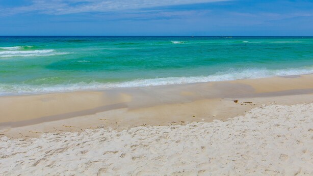 Ein Strand mit klarem türkisblauem Wasser und einem Sandufer.