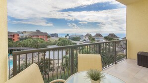 Ein Balkon mit Blick auf eine Wohngegend, einen Pool und einen klaren Himmel.