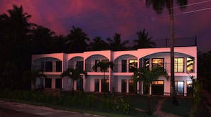 A multi-story building with balconies and arched windows, surrounded by palm trees. - Malinao View Beach Resort (General Luna)