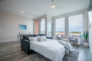 Enjoy a restful night's sleep in this spacious bedroom with a large bed and stunning city and beach views.