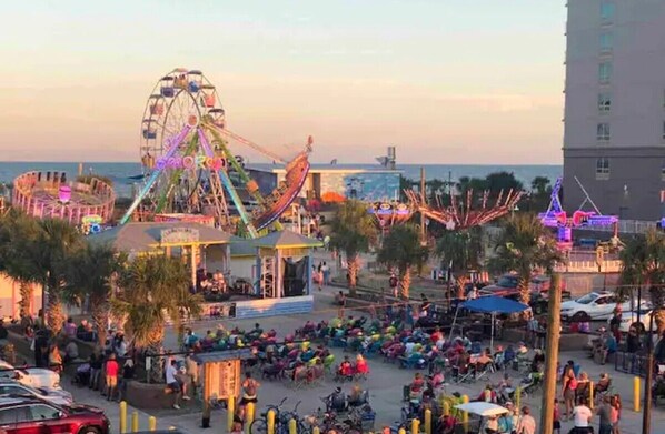 Un parque de atracciones al aire libre concurrido, con noria y diversas atracciones.