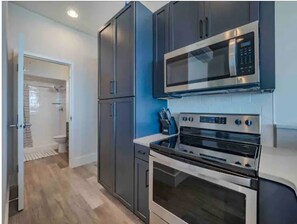 A modern kitchen with dark cabinets, a stainless steel microwave, and an oven. - Best Ocean & Boardwalk Views of Carolina Beach! ~ Kalypso's Nest (Carolina Beach,)