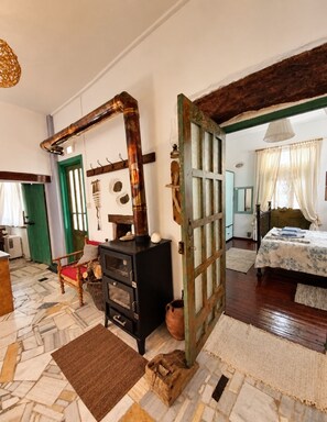 A room with a bed, a wooden cabinet, a mirror, and a door leading to another room.