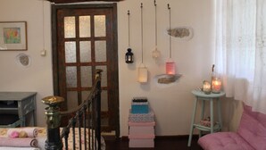 A cozy room with a wooden staircase, a door with frosted glass panels, and a small table with candles and jars.