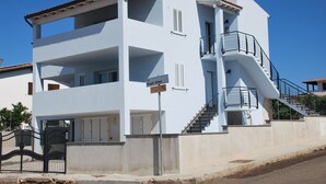 A white multi-story building with a balcony, a staircase, and a gate. - Vacation in the House of Dreams (Portoscuso)