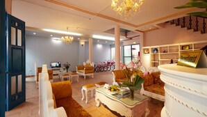 A spacious living room with a chandelier, comfortable seating, a television, and a bicycle in the background. - Lucky Budda Inn Villa (Hanoi)