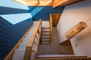 A staircase with wooden railings and a woven light fixture.