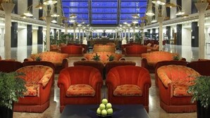 A spacious lobby with a high wooden ceiling, red upholstered seating, and a central black table with fruit. - Marriott Park hotel Rome (Lazio)