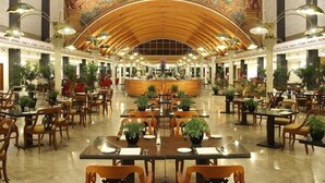 A spacious hotel lobby with a high arched ceiling, a central bar area, and numerous tables and chairs. - Marriott Park hotel Rome (Lazio)