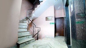 A marble staircase leading to a door with a fire exit sign. - Hotel Holiday Comfort - 800 mts from Jallianwala Bagh, Amritsar (Amritsar)