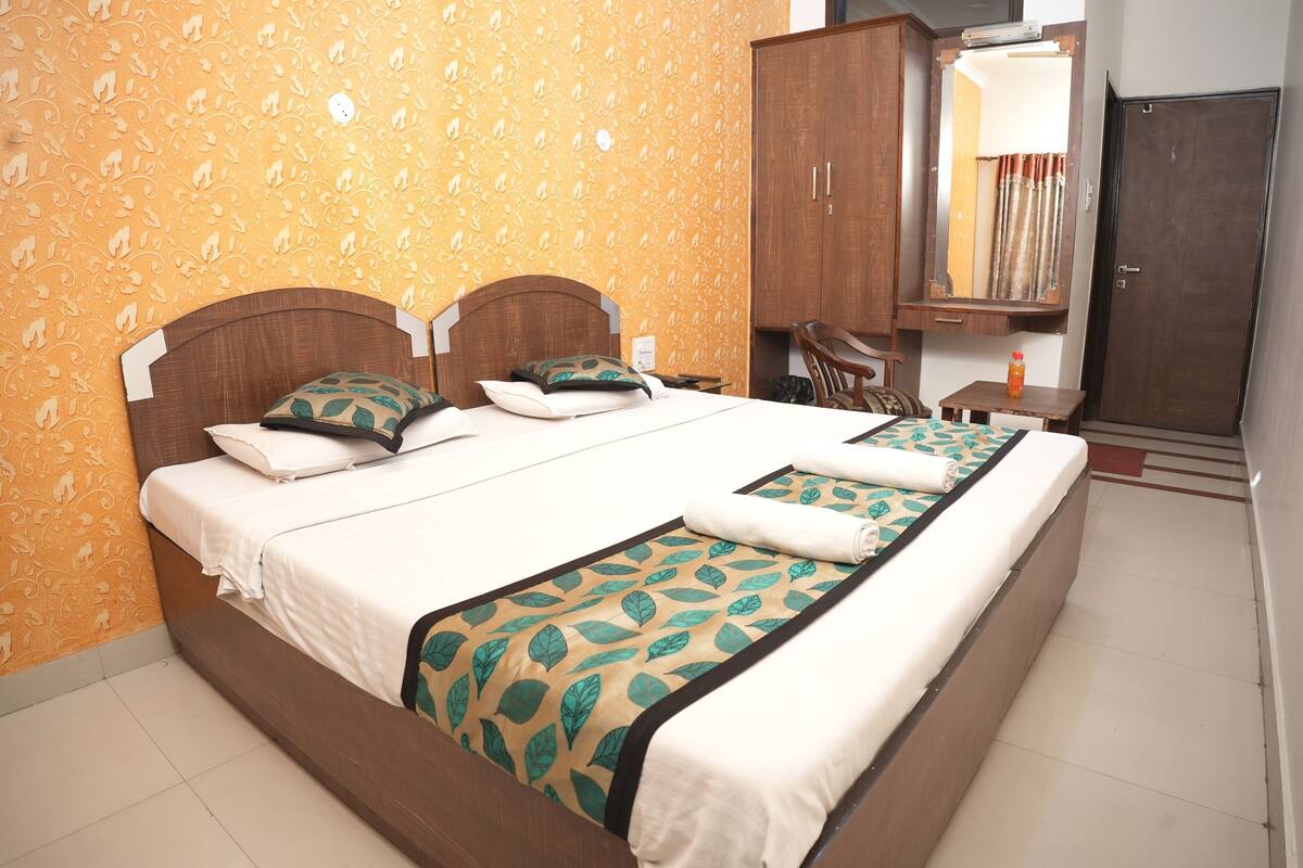 A hotel room with a large bed, a wooden wardrobe, a mirror, and a small table.