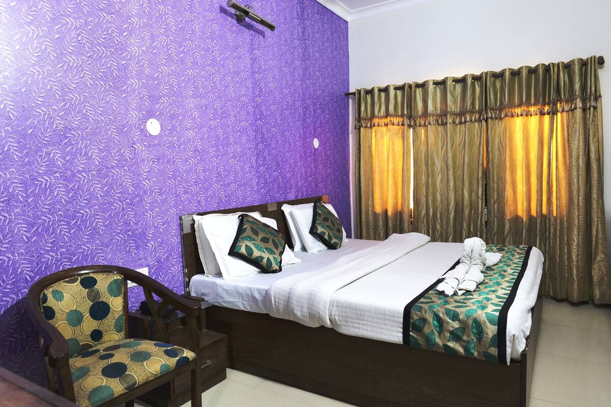 A hotel room with a bed, a chair, and a window with curtains.