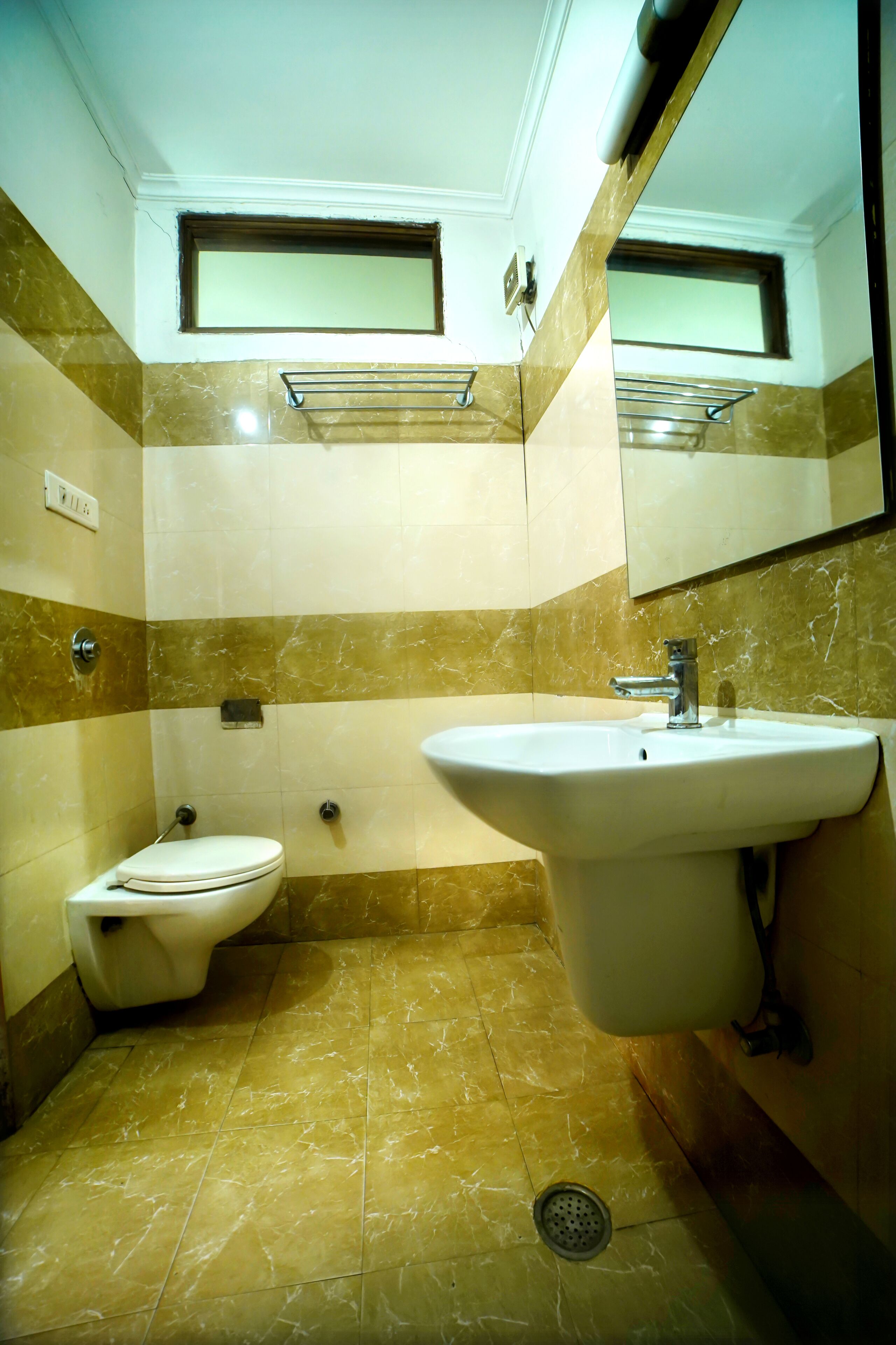 Een badkamer met toilet, wastafel en spiegel.