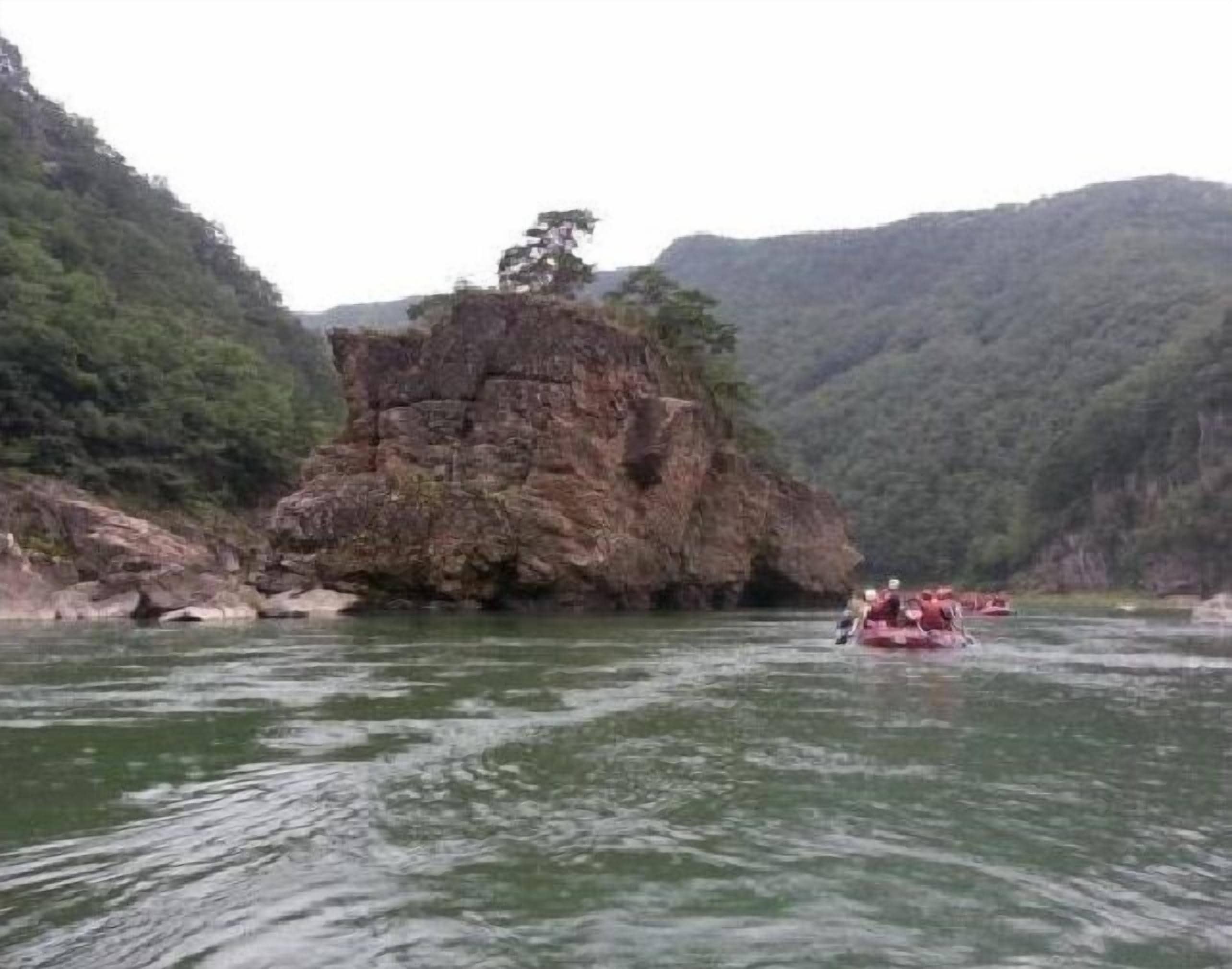 Un río con un afloramiento rocoso y un grupo de personas en una balsa.