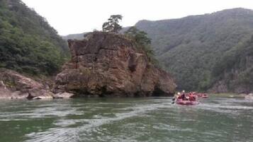 Un río con un afloramiento rocoso y un grupo de personas en una balsa.