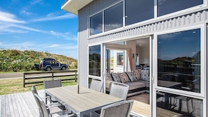 Uma casa moderna com deck, área de refeições e um sofá.