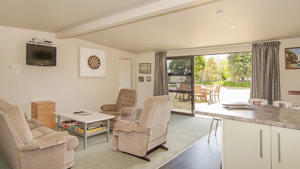 A modern living room with a sofa, two armchairs, a coffee table, and a flat-screen TV mounted on the wall.