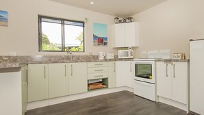 A modern kitchen with white cabinets, a microwave, an oven, and a window with a view of greenery.