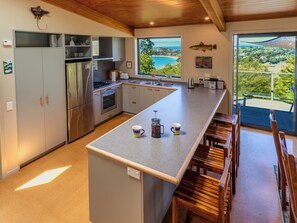 Una cocina moderna con una isla grande, electrodomésticos de acero inoxidable y vista al mar.