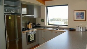 Una cocina moderna con electrodomésticos de acero inoxidable, un ventanal y vista al mar.
