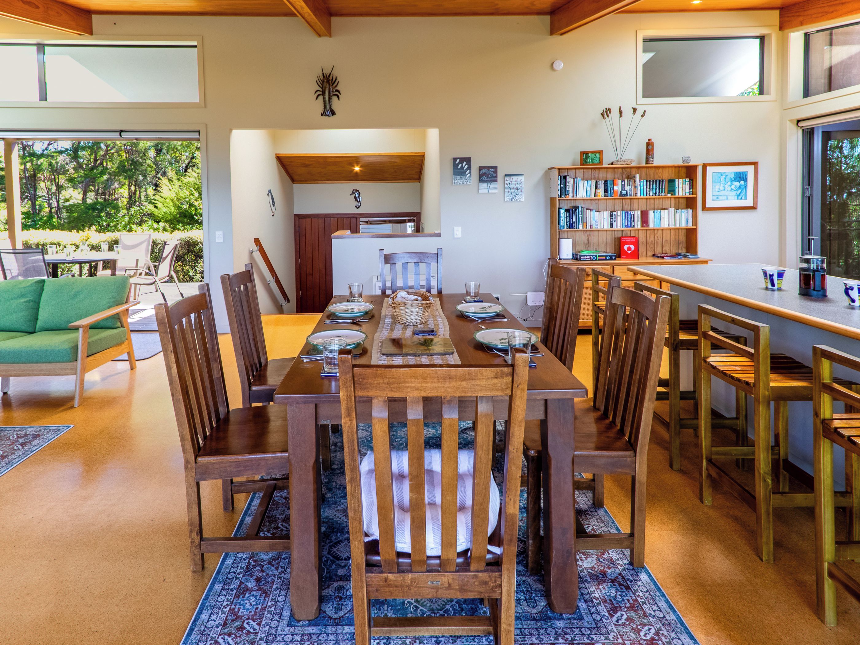 A dining area with a long wooden table, chairs, and a bookshelf.