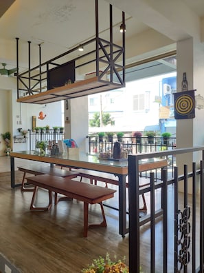 A modern interior with a glass-top table, wooden benches, and a decorative wall with a dartboard.