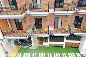 A multi-story residential building with balconies, outdoor seating, and a small garden area.