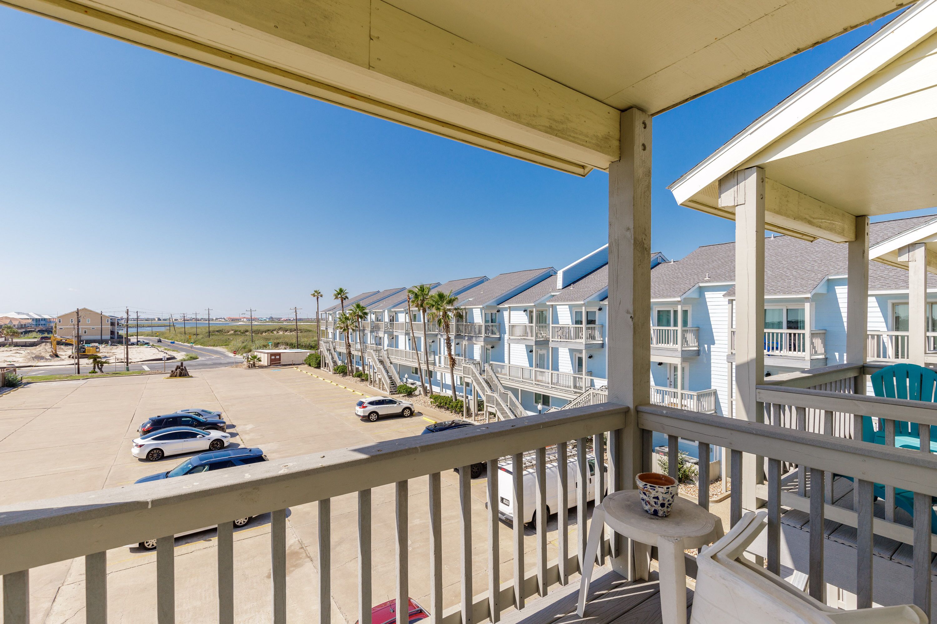 Ein Balkon mit Blick auf einen Parkplatz und eine Reihe von Gebäuden am Strand.