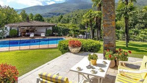 A pool area with a patio, seating, and a view of a mountain. - Mountain view villa with private pool near Costa Brava (Gerona / Girona)