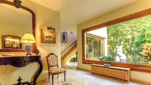 A spacious living room with a large window, a wooden staircase, and a decorative mirror. - Mountain view villa with private pool near Costa Brava (Gerona / Girona)