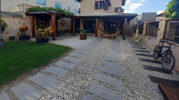 Une cour avec un chemin de pierre menant à un bâtiment doté d’un toit en tuiles et d’un hamac.