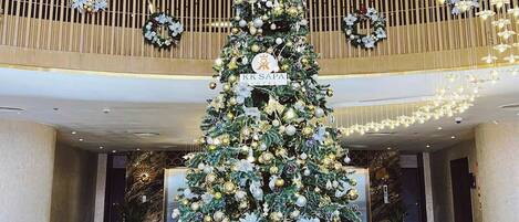 A grand lobby with a large Christmas tree, modern lighting, and a marble floor.