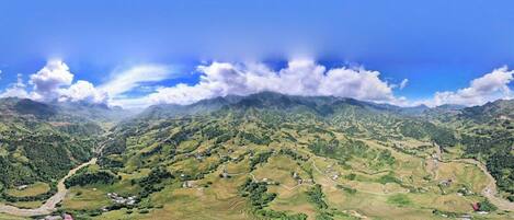 Una vista panorámica de un paisaje montañoso con campos en terrazas y casas dispersas.