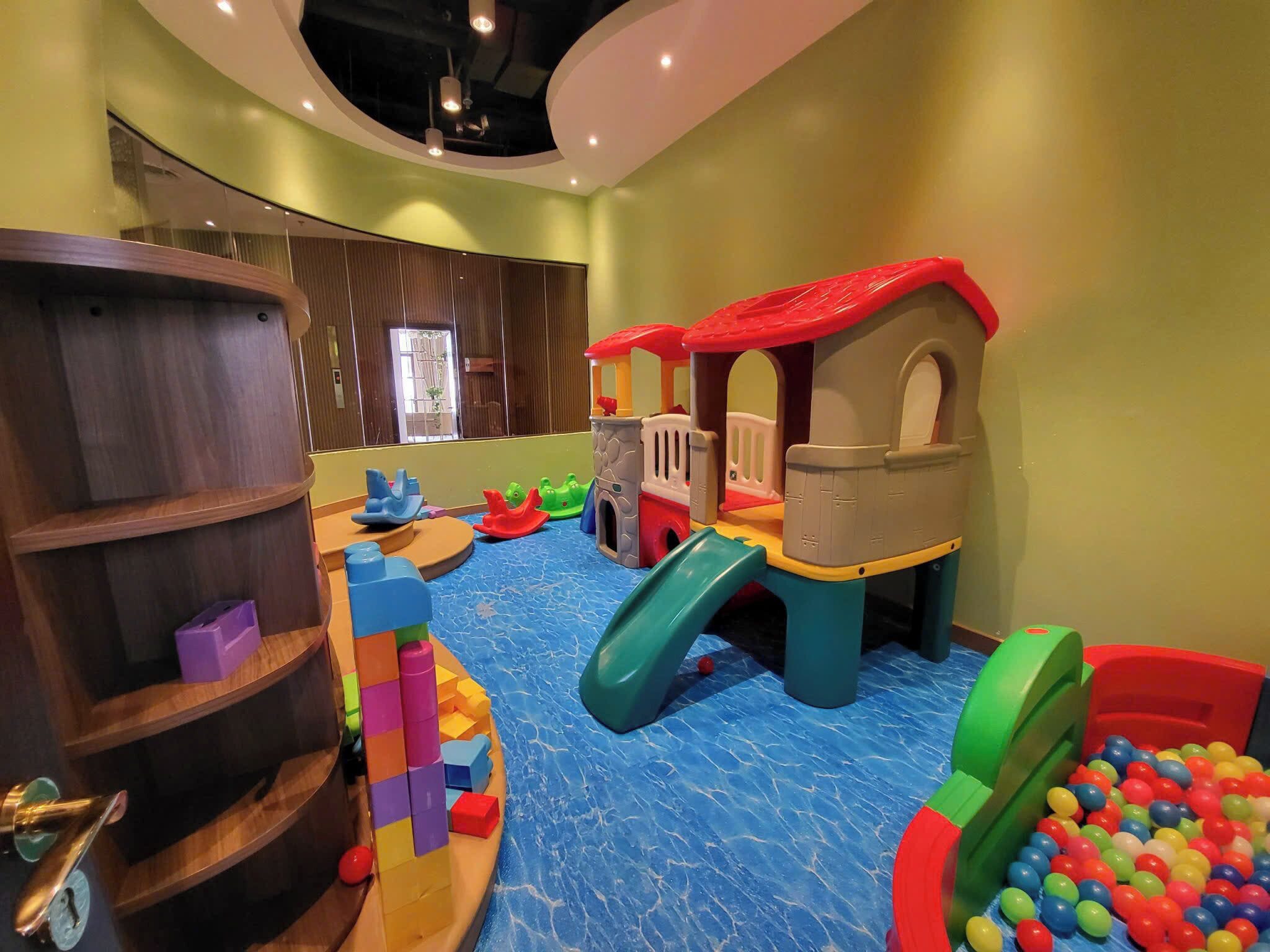 Zona de juegos infantiles con tobogán, estructuras para escalar y piscina de pelotas.