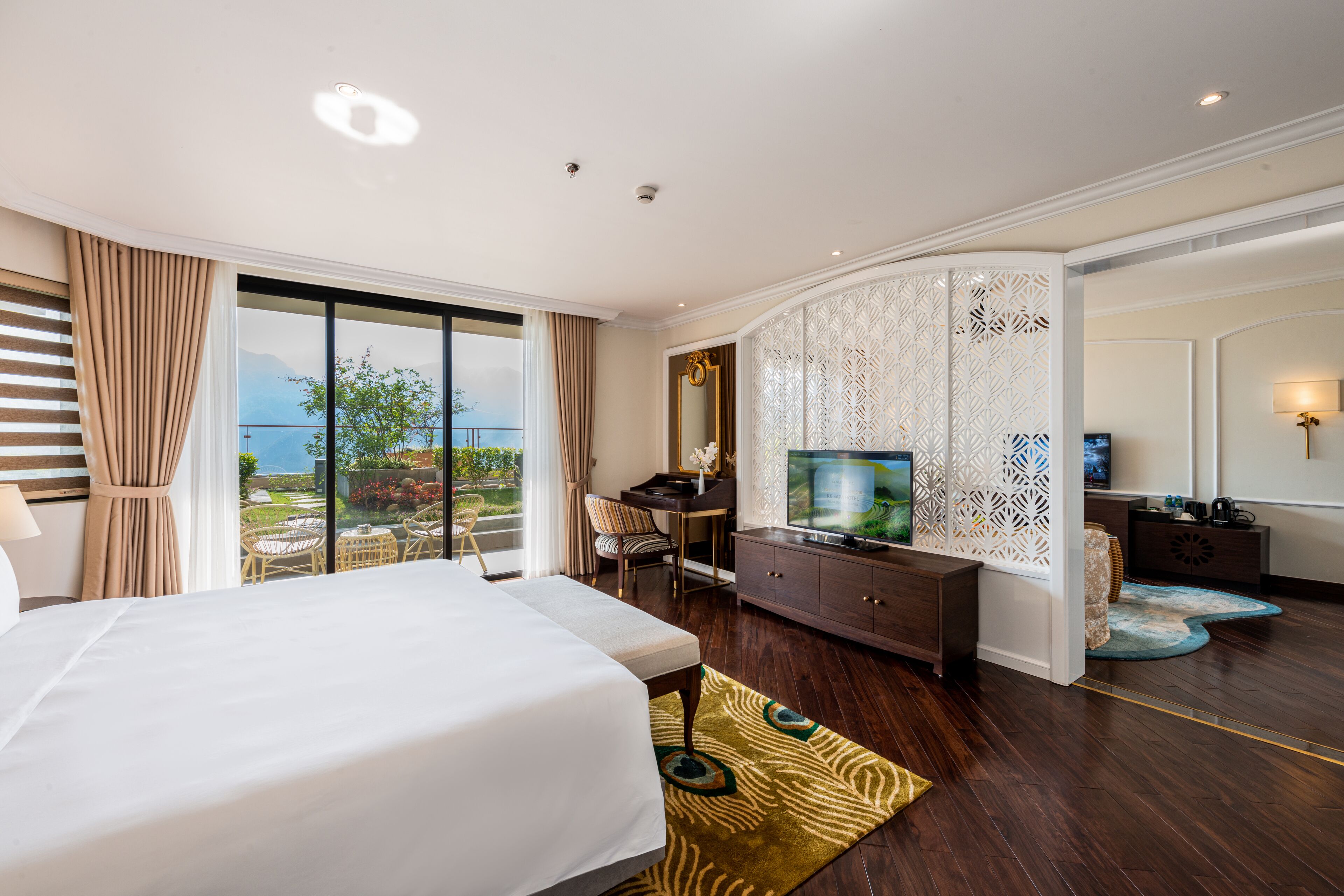 A hotel room with a large bed, a desk, a television, and a view of the outdoors.