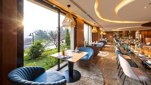 Un comedor moderno con mesas redondas, sillas tapizadas en azul e iluminación colgante.