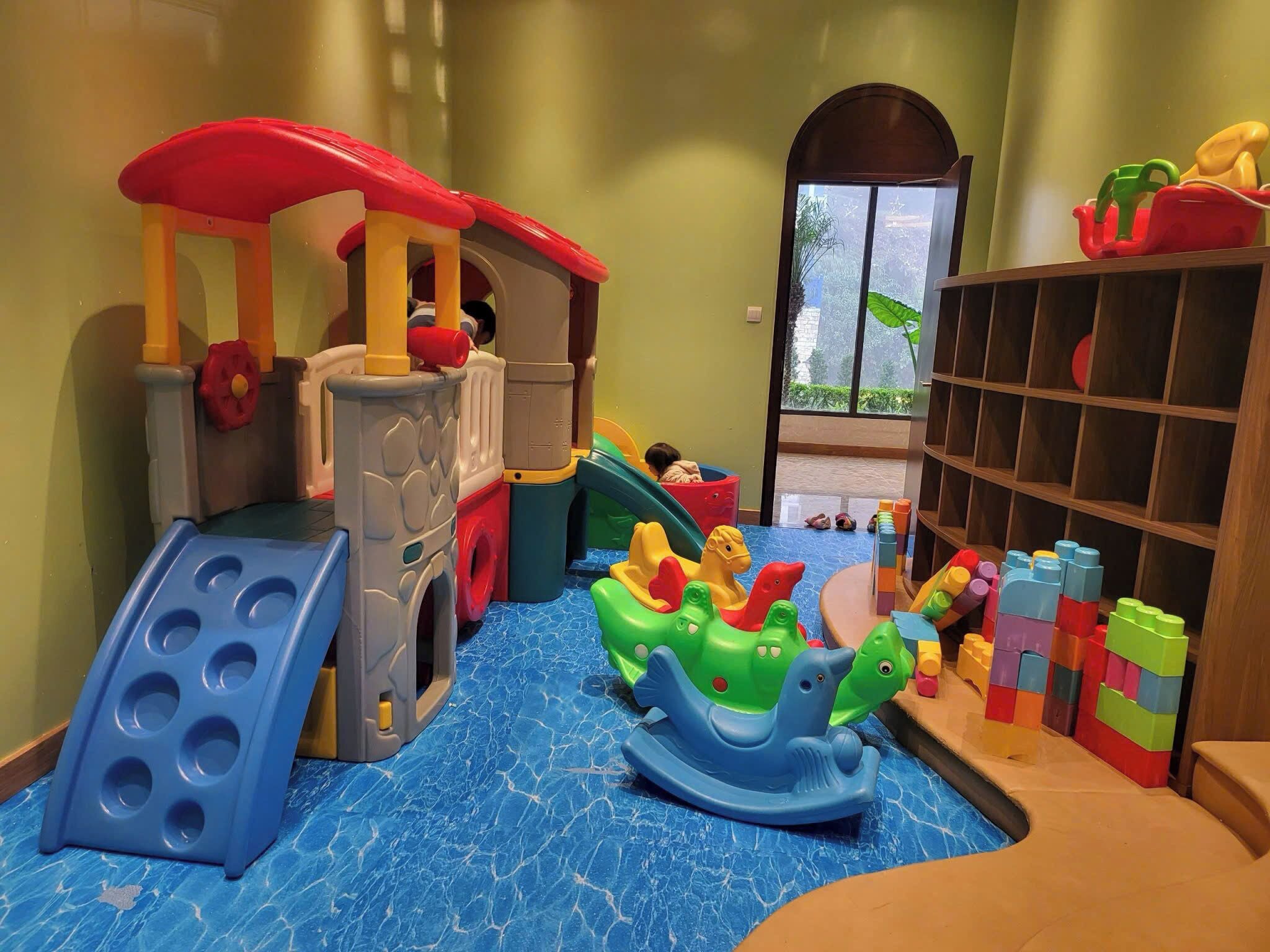 Een kinderspeelplaats met een glijbaan, klimconstructie en diverse speelgoed.