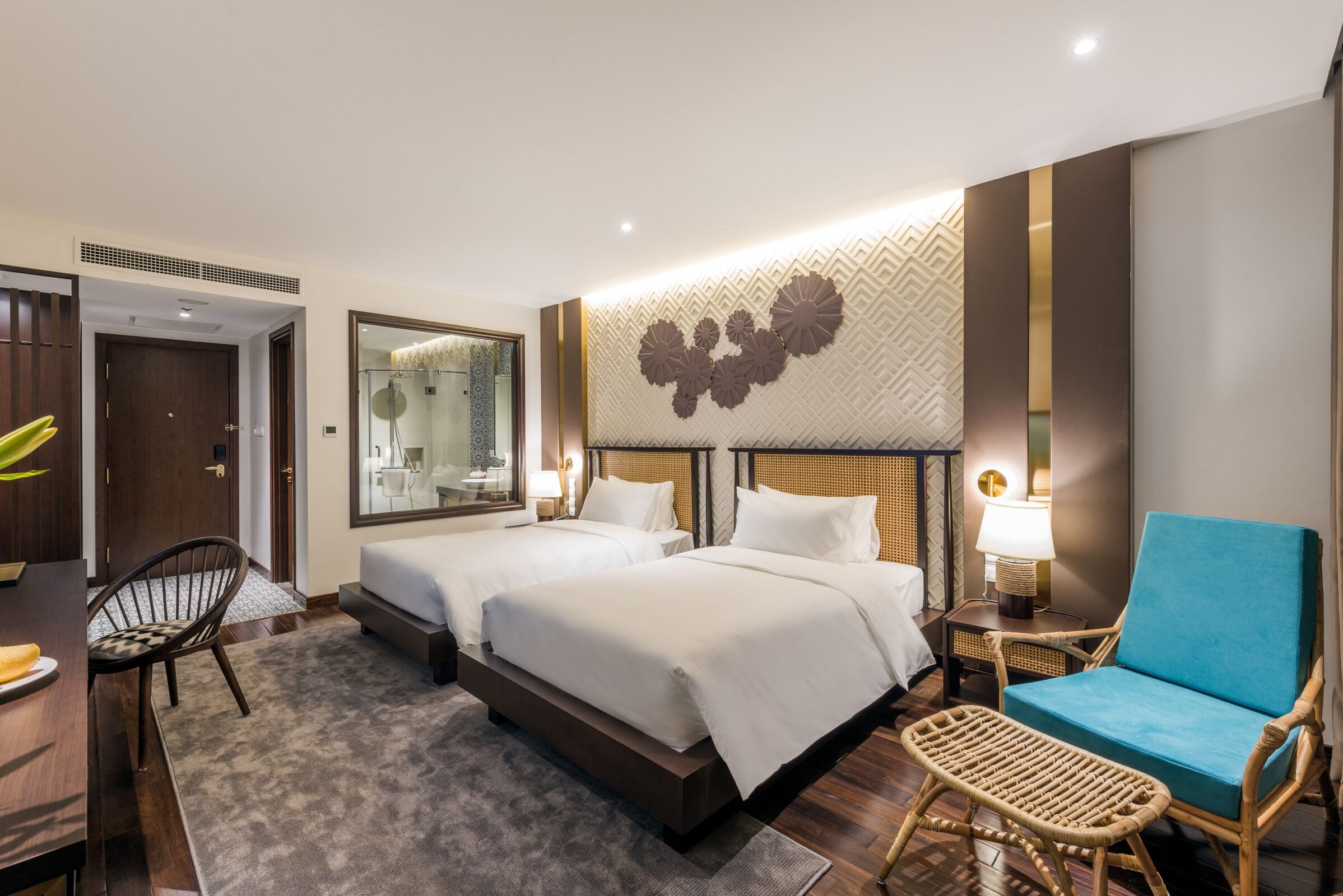 Habitación de hotel con dos camas, un escritorio, una silla y una lámpara.
